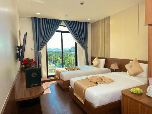 a hotel room with two beds and a large window at Tokyo Hotel Phan Rang in Thôn Mỹ Phước