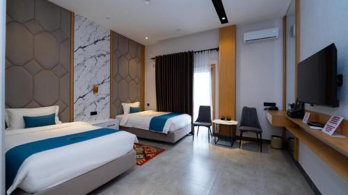 a hotel room with two beds and a flat screen tv at Parliament Palace Hotel in Khujand