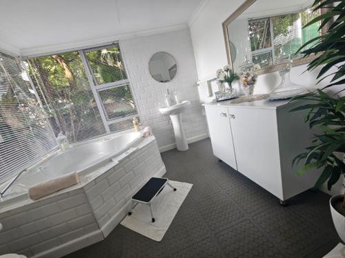 a bathroom with a tub and a sink and a chair at African Diamond - Date Night Suite in Benoni