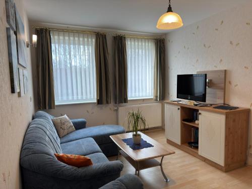 a living room with a blue couch and a tv at Charmante Ferienwohnung mit Garten in Wiek in Wiek auf Rügen