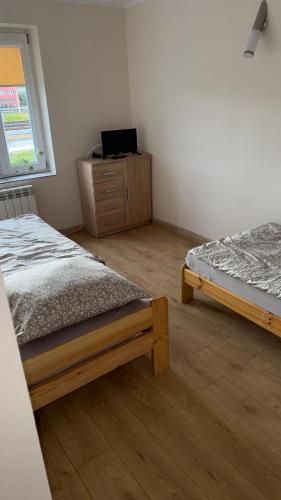 a bedroom with two beds and a dresser and a window at Apartament 10 Słoneczna in Ełk