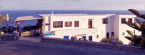 a white house with the ocean in the background at Hermes-Ios Rooms To Let in Ios Chora