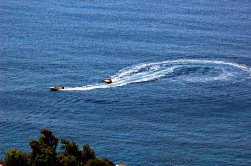 a boat making a wake in the water at Hermes-Ios Rooms To Let in Ios Chora