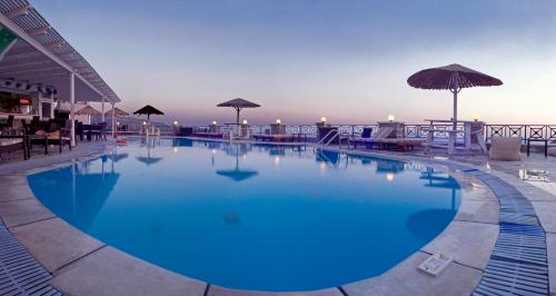 a large blue pool with tables and umbrellas at Hermes-Ios Rooms To Let in Ios Chora