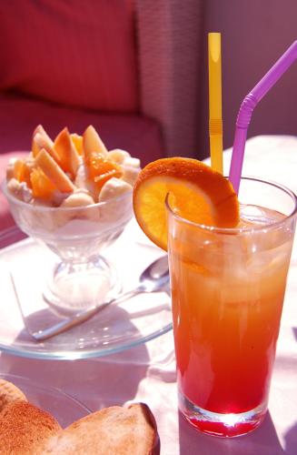 a glass of orange juice next to a bowl of fruit at Hermes-Ios Rooms To Let in Ios Chora