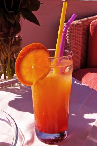 a glass of orange juice with a straw and an orange slice at Hermes-Ios Rooms To Let in Ios Chora