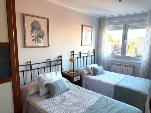 a bedroom with two beds and a window at A CALZADA in Cambados