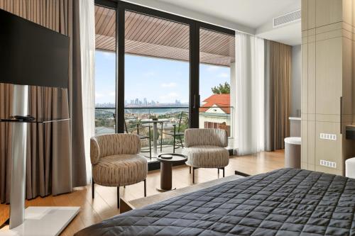 a bedroom with a bed and two chairs and a large window at Arbor Hotel - Signature Collection in Istanbul