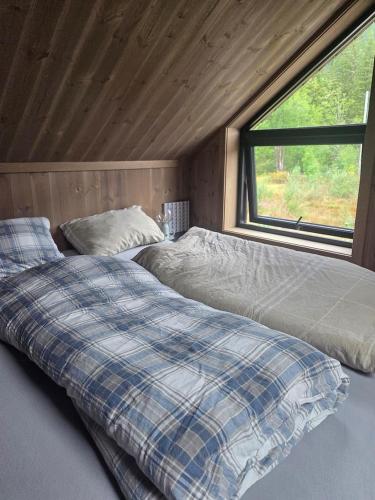 a couple of beds in a room with a window at Cabin With Dock By Otra In Setesdal in Bygland