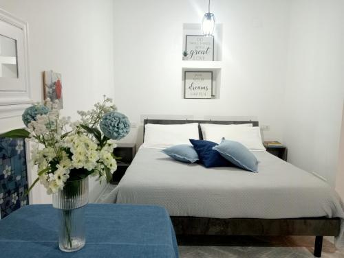 a bedroom with a bed with a vase of flowers on a table at San Giovanni Apartment in Catanzaro
