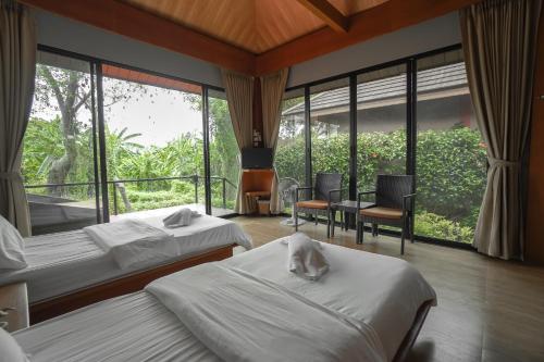 a hotel room with two beds and a balcony at The Grace Amphawa in Amphawa