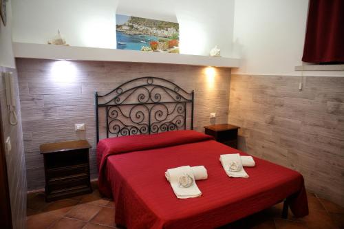 a bedroom with a red bed with two towels on it at Palazzo Dei Corsari in Trapani