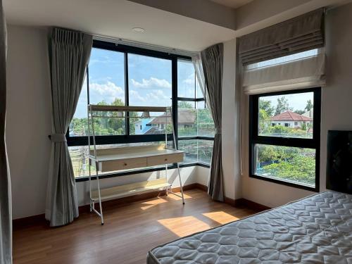 a bedroom with a desk and large windows at Msthouse in Ban Bang Phun