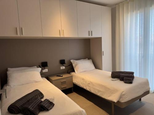 two beds in a small room with white cabinets at A&G Elettra flat a pochi passi dal mare e Venezia in Cavallino-Treporti