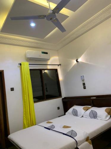 two beds in a room with a ceiling fan at 2 chambres salon au calme in Porto-Novo