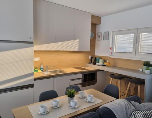 a kitchen with a table and chairs and a kitchen with white cabinets at Apartmán Nad Arénou NMNM in Nové Město na Moravě