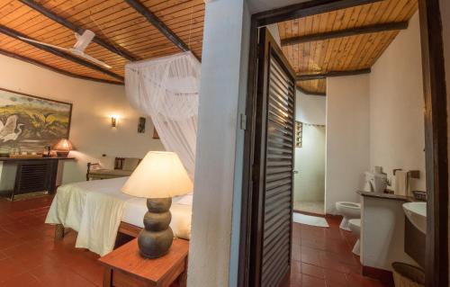a bedroom with a bed and a table with a lamp at Baobab Sea Lodge in Kilifi