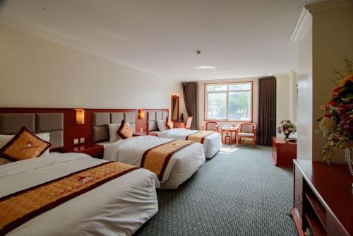 a hotel room with three beds and a window at Lao Cai Royal Hotel in Lao Cai