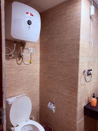 a bathroom with a toilet and a toilet paper dispenser at Luxury Couple Friendly Studio in Dehradun