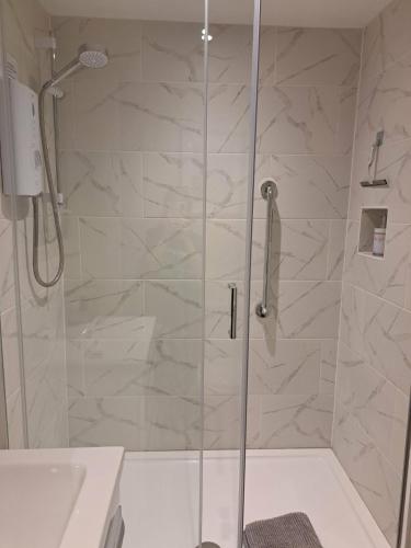 a shower with a glass door in a bathroom at Bow Cottage in Bridport