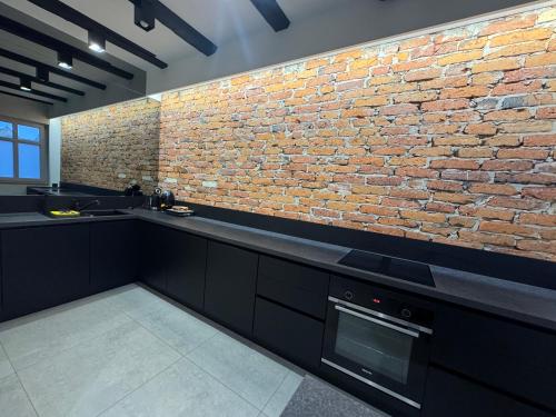 a kitchen with a brick wall and black counters at 5 Star Apartments - Luxury & Comfort in Jelenia Góra