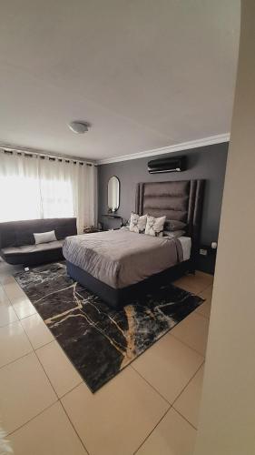 a bedroom with a large bed and a couch at Palma Spaces in Pretoria