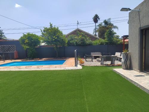 a yard with green grass and a swimming pool at Palma Spaces in Pretoria