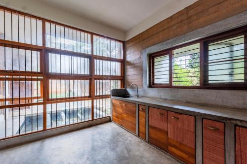 a kitchen with wooden cabinets and large windows at Elite Villa - By Purvish Hospitalities in Bangalore