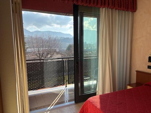 a bedroom with a bed and a balcony with a view at Albergo Valle d'Oro in Albino