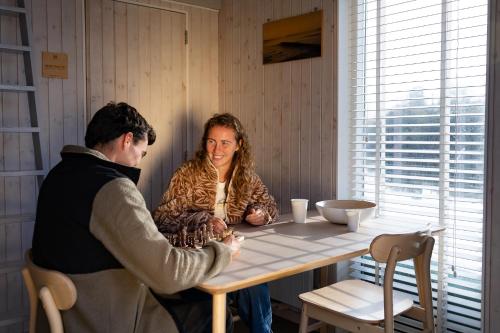 a woman sitting at a table with a man at Brouwersdam Stay in Ouddorp