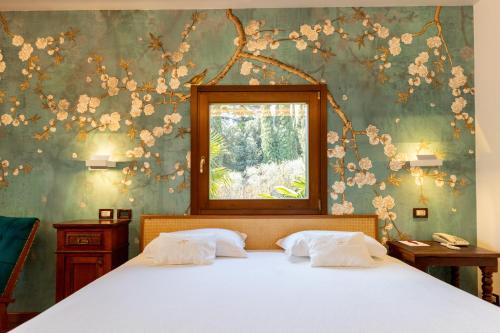 a bedroom with a bed with a flowery wall at Villa Madrina Lovely and Dynamic Hotel in Garda
