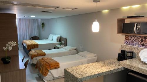 a hotel room with three beds and a kitchen at Nobile Imperial Flat in João Pessoa