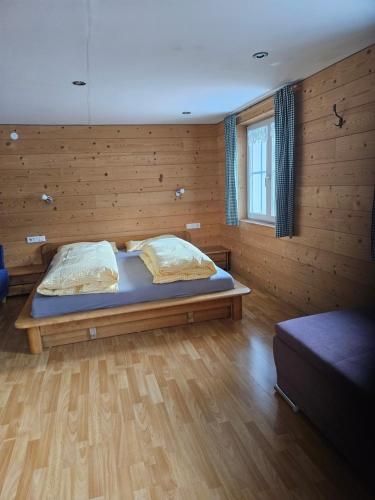 a bedroom with a bed and a wooden wall at Ferienhaus Schindeler in Mellau