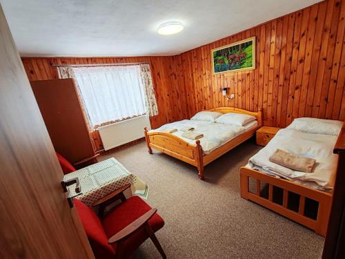 a small bedroom with two beds and a chair at ZorHouse Ždiar in Ždiar