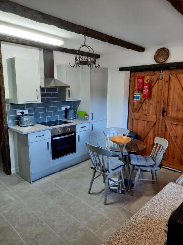 a kitchen with a table and a table and chairs at The Barn at Creech View in Wareham