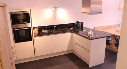 uma cozinha com armários brancos e um balcão preto em Appartement Seejoch em Seefeld no Tirol