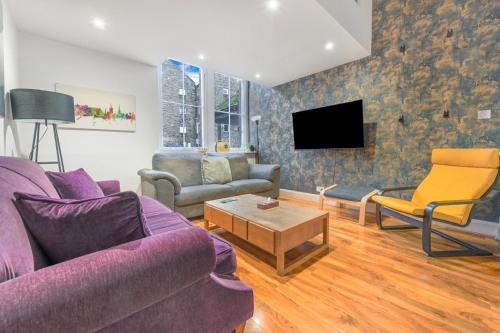 a living room with a purple couch and a tv at The Old School in Dean Village in Edinburgh