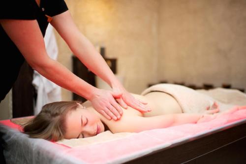 a woman laying on a bed getting a massage at Aqua Center Apartments in Druskininkai