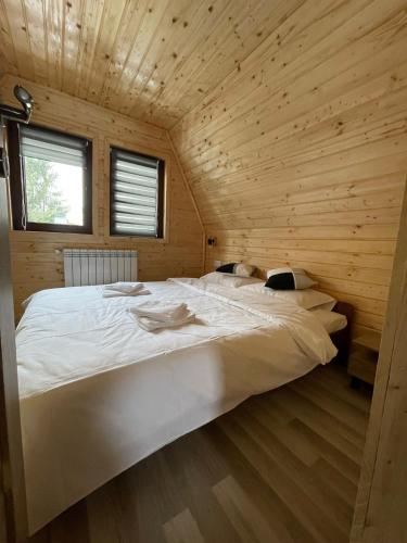 a bedroom with a large white bed in a wooden room at Cabana De Peste Gard in Topliţa