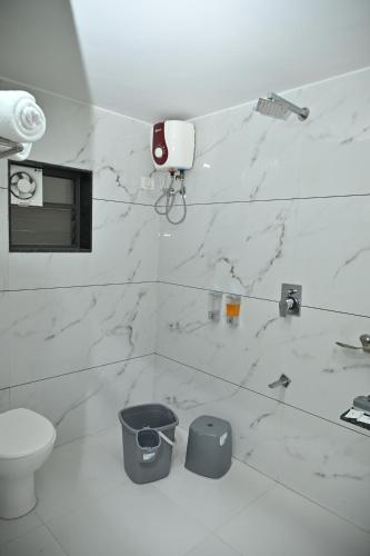 a bathroom with white marble walls and a toilet at Hotel Shree Niwas Inn Near Airport in Jāmb