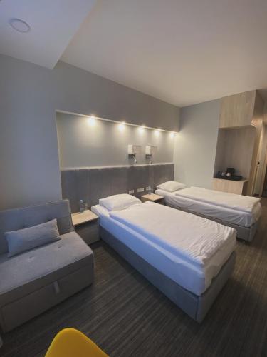 a hotel room with two beds and a couch at Hotel Cztery Korony in Śrem