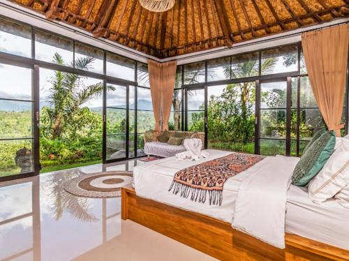 a bedroom with a bed in a room with windows at Ritual Ubud in Gianyar
