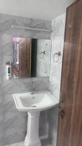 a bathroom with a white sink and a mirror at Full Moon Home Stay in Jamania