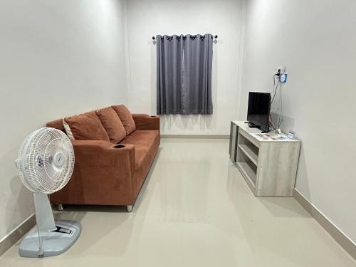 a living room with a brown couch and a fan at Family house villa in Ban Rai Yai