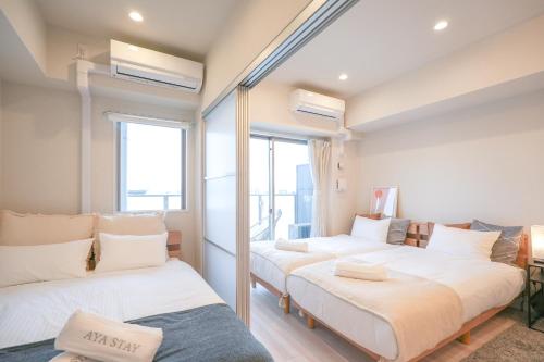two beds in a room with two windows at AYA Residence大阪城公園 Osaka Castle JR Morinomiya 徒歩5min in Osaka