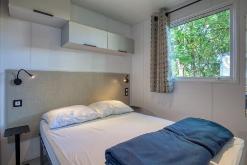 a small bedroom with a bed with a window at Camping Le Bosquet in Domme