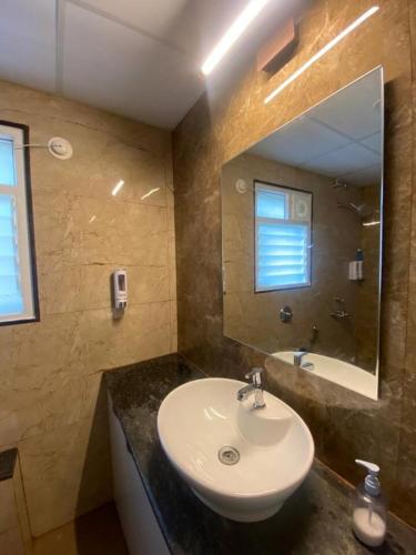 a bathroom with a sink and a mirror and a tub at Nirvana Villa Karjat in Dhamni