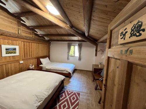 a bedroom with two beds in a room with wooden walls at Horn Seaside Homestay in Nangan