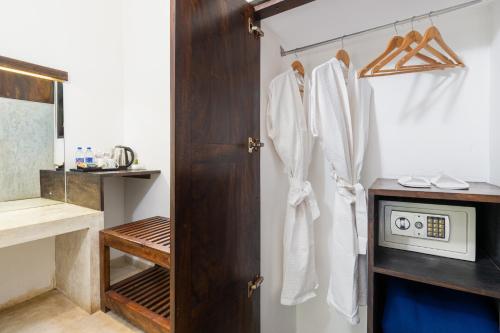 a bathroom with a wooden closet with white robes at Serendib Signature Resort in Digana