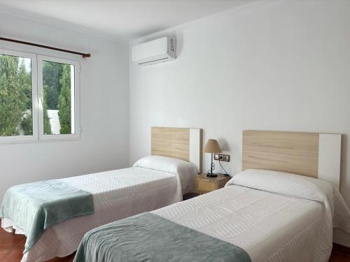 two beds in a white room with a window at Villa Sa Punta in Cala en Blanes